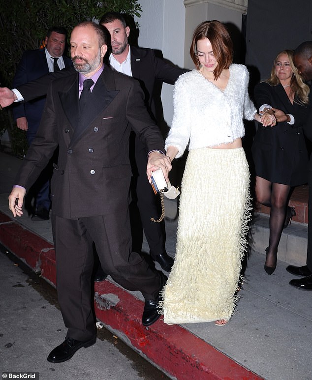 Emma Stone in a fuzzy white v-neck cardigan and cream floor-length skirt