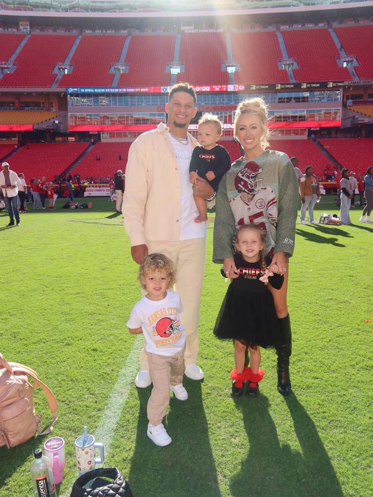 Patrick Mahomes and Brittany Mahomes with their two children on a football field.