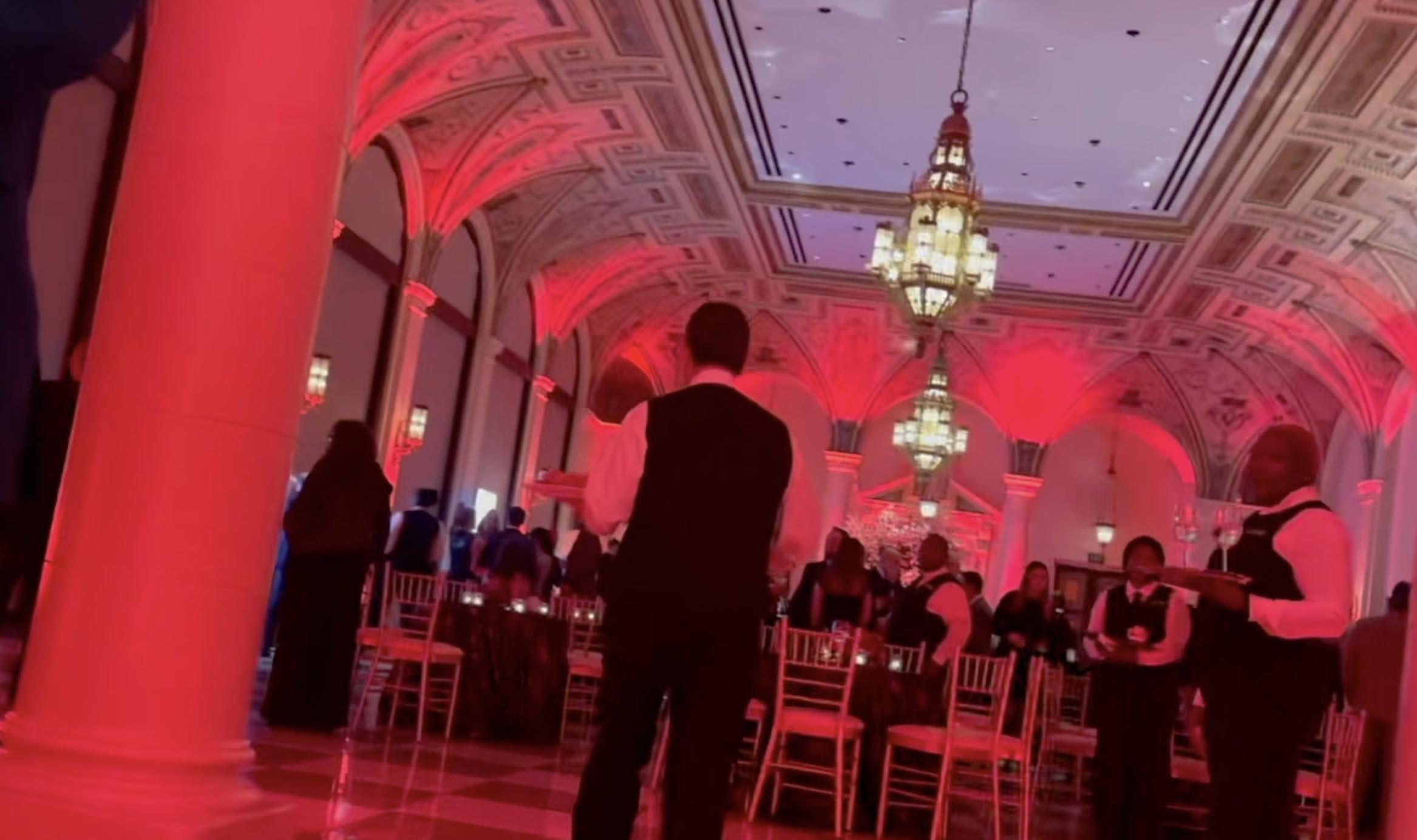 Guests mingling in a ballroom with red lighting and checkered floors at The Breakers.