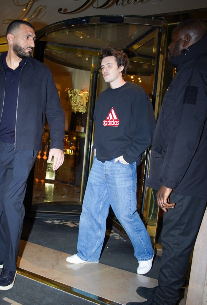 Cruz Beckham wearing a black Adidas sweatshirt, light blue baggy jeans, and white sneakers, arriving at Restaurant Kaspia in Paris.