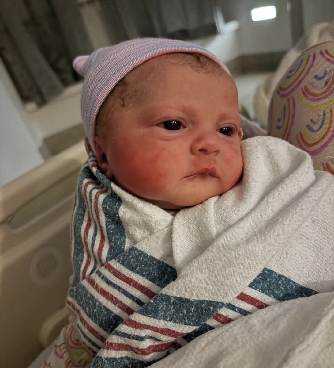 Meghan Trainor and Daryl Sabara smiling with newborn Mikey Moon nestled between them.