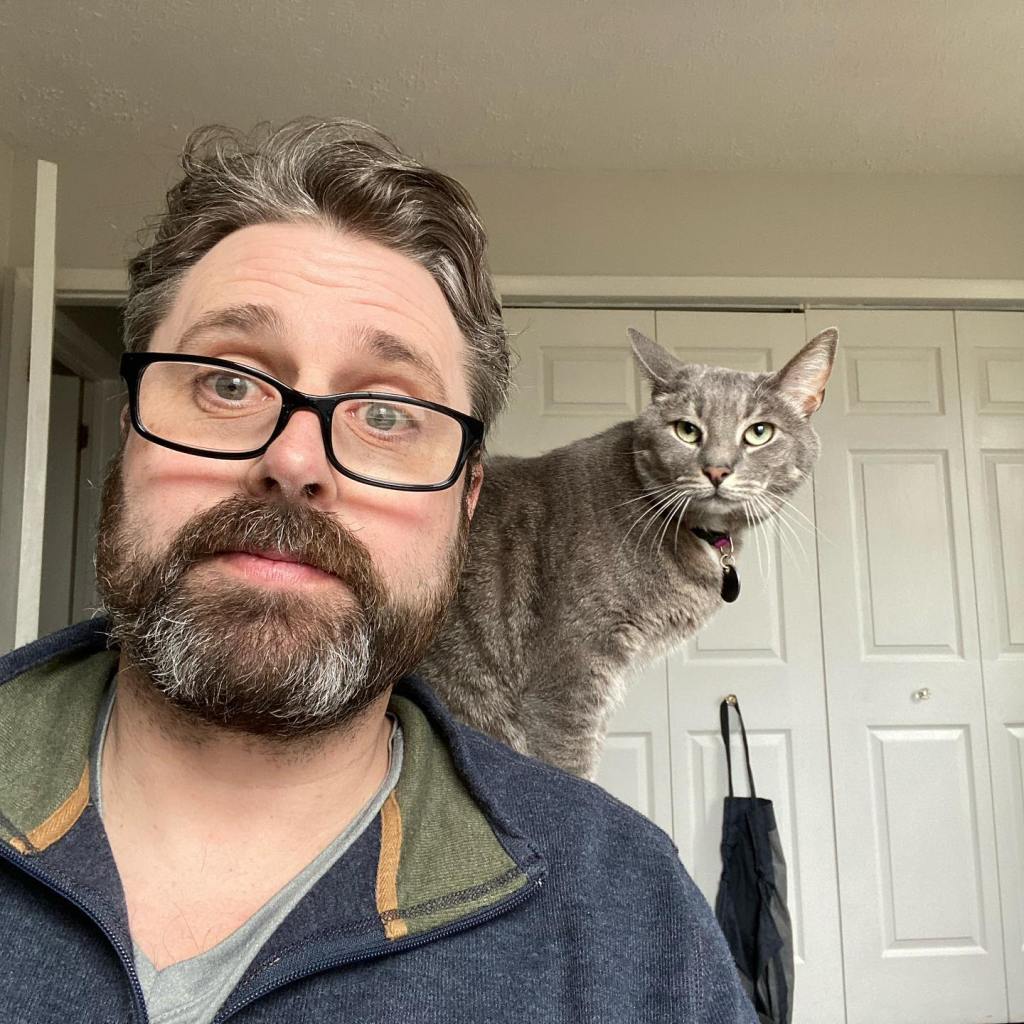 Mark Orchard, Savannah Guthrie's first husband, posing with a gray cat on his shoulder.