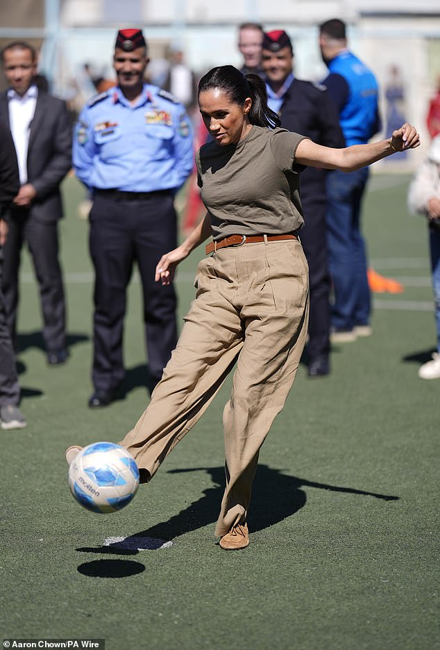 Meghan Markle takes a penalty kick as women and children look on during a visit in Jordan.