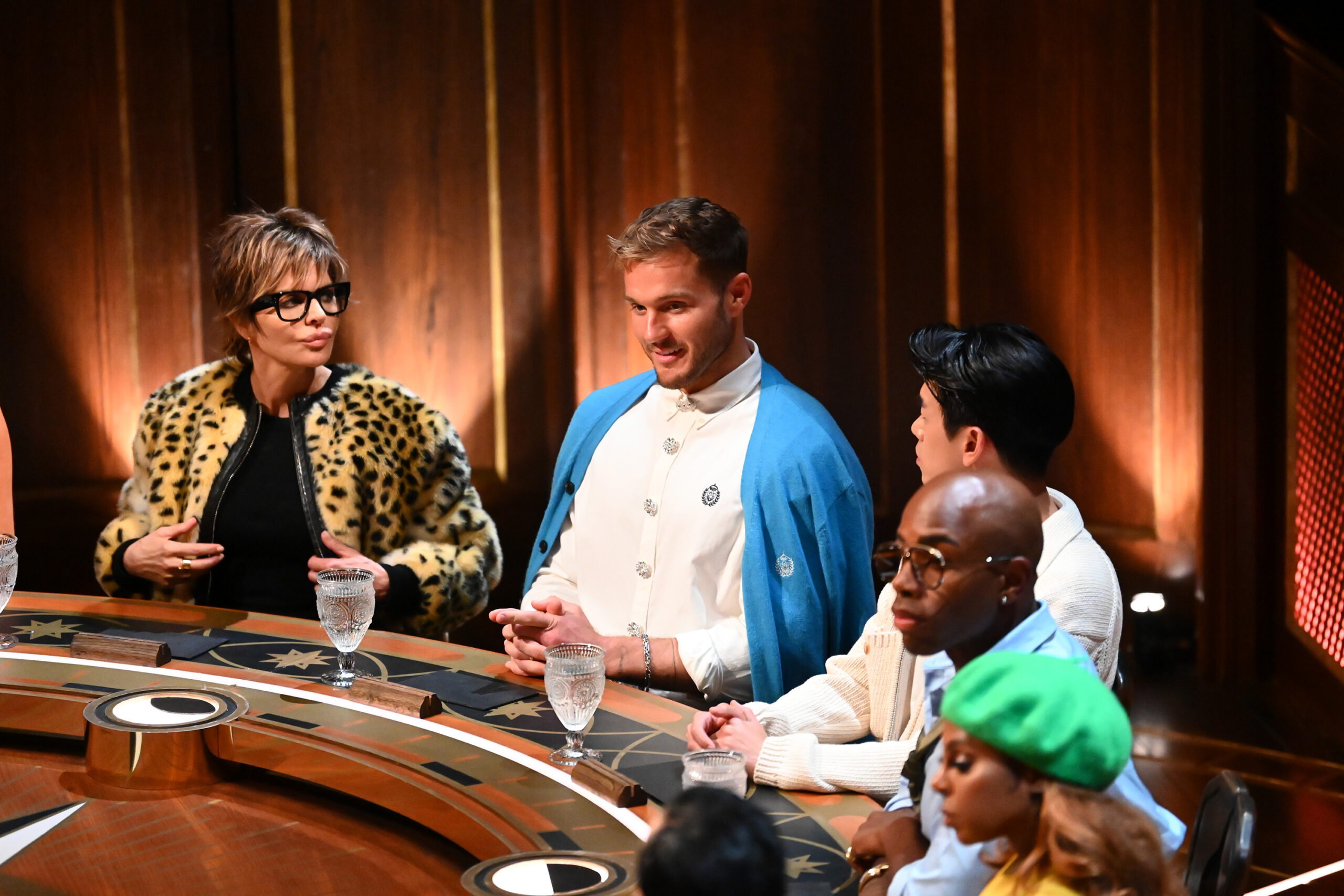 Lisa Rinna and Colton Underwood seated with castmates at The Traitors round table during Season 4.