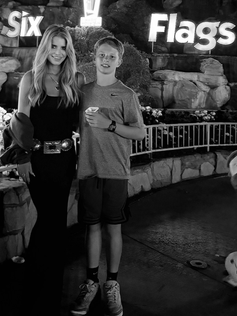 Jessica Simpson and her son Ace standing in front of the Six Flags sign.