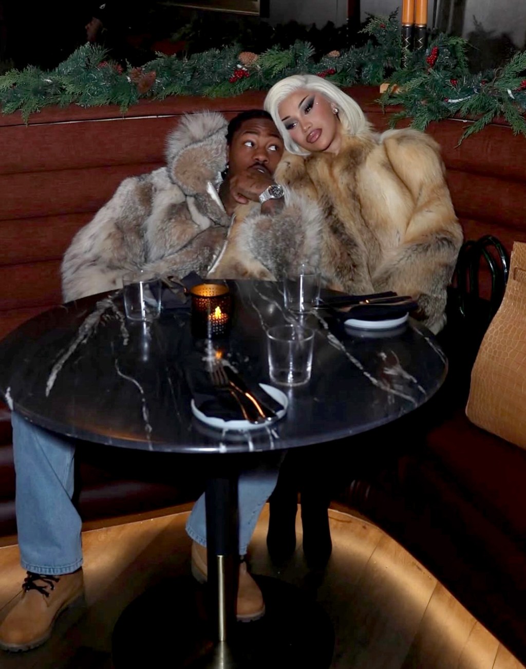 Cardi B and Stefon Diggs seated together at a restaurant.