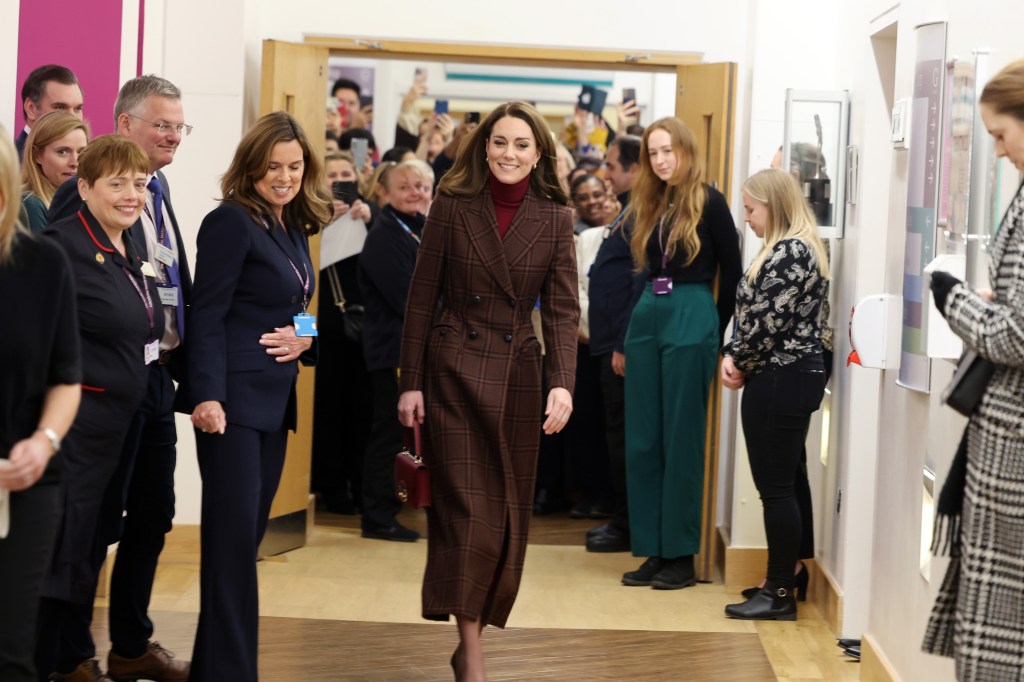 Catherine, Princess of Wales, smiles while walking through a hospital hallway.