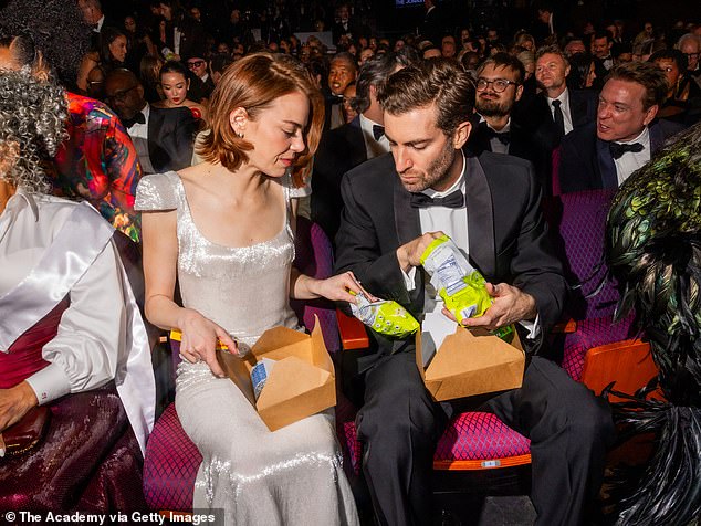 Attendees seated at the Oscars ceremony with snack boxes under the seats