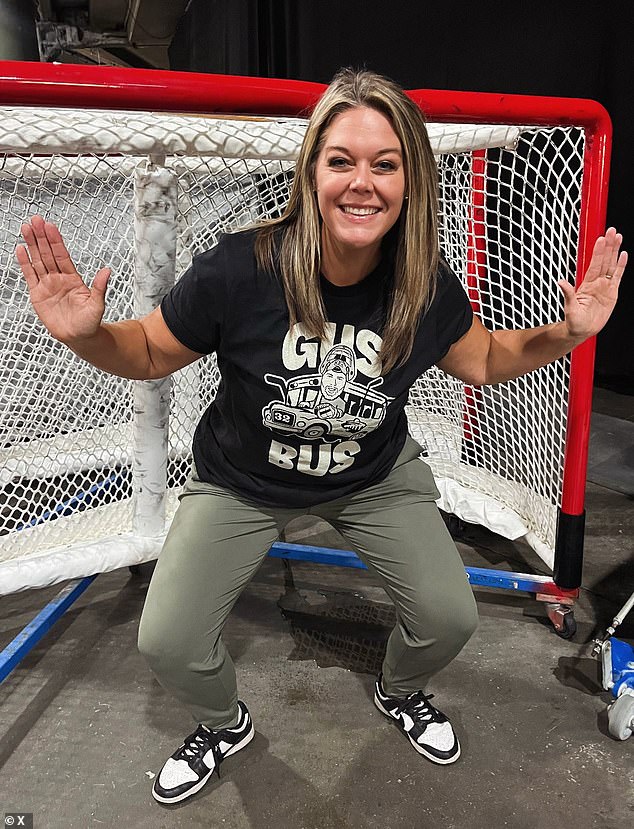 Jessi Pierce smiling from inside a hockey goal, wearing a T-shirt honoring Wild goalie Filip Gustavsson