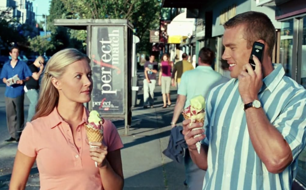 Carrie Anne Fleming and a man in a striped shirt holding ice cream cones on a city street.