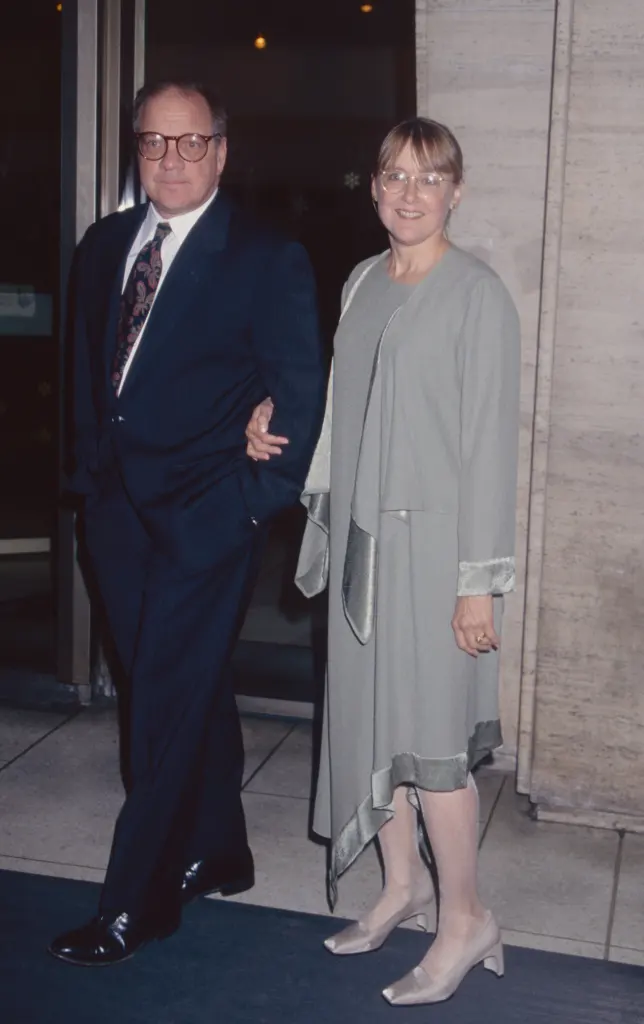 Mary Beth Hurt in a gray dress holding the arm of a man in a suit.