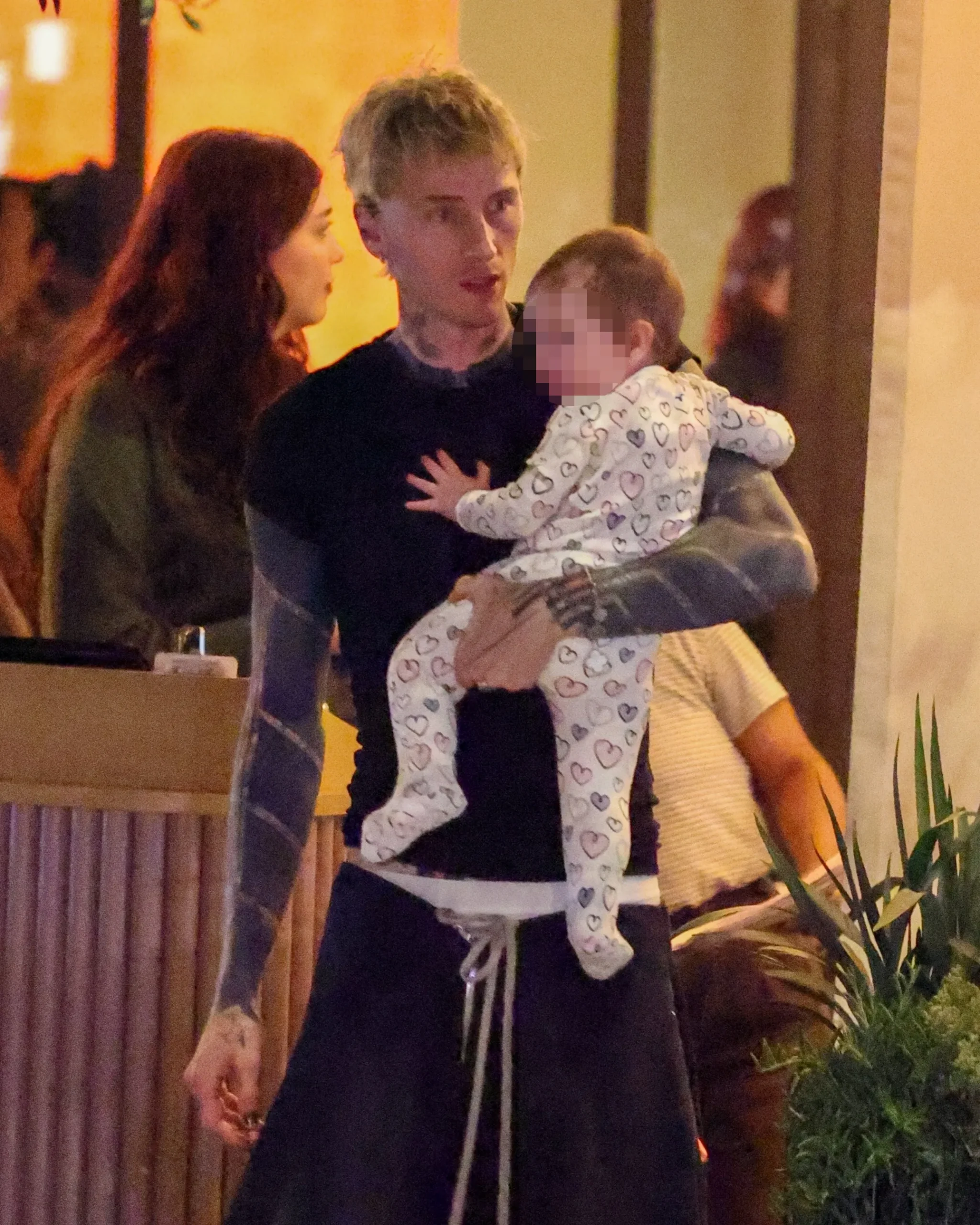 Machine Gun Kelly holds daughter Saga during a January outing in Calabasas as Megan Fox stands nearby.