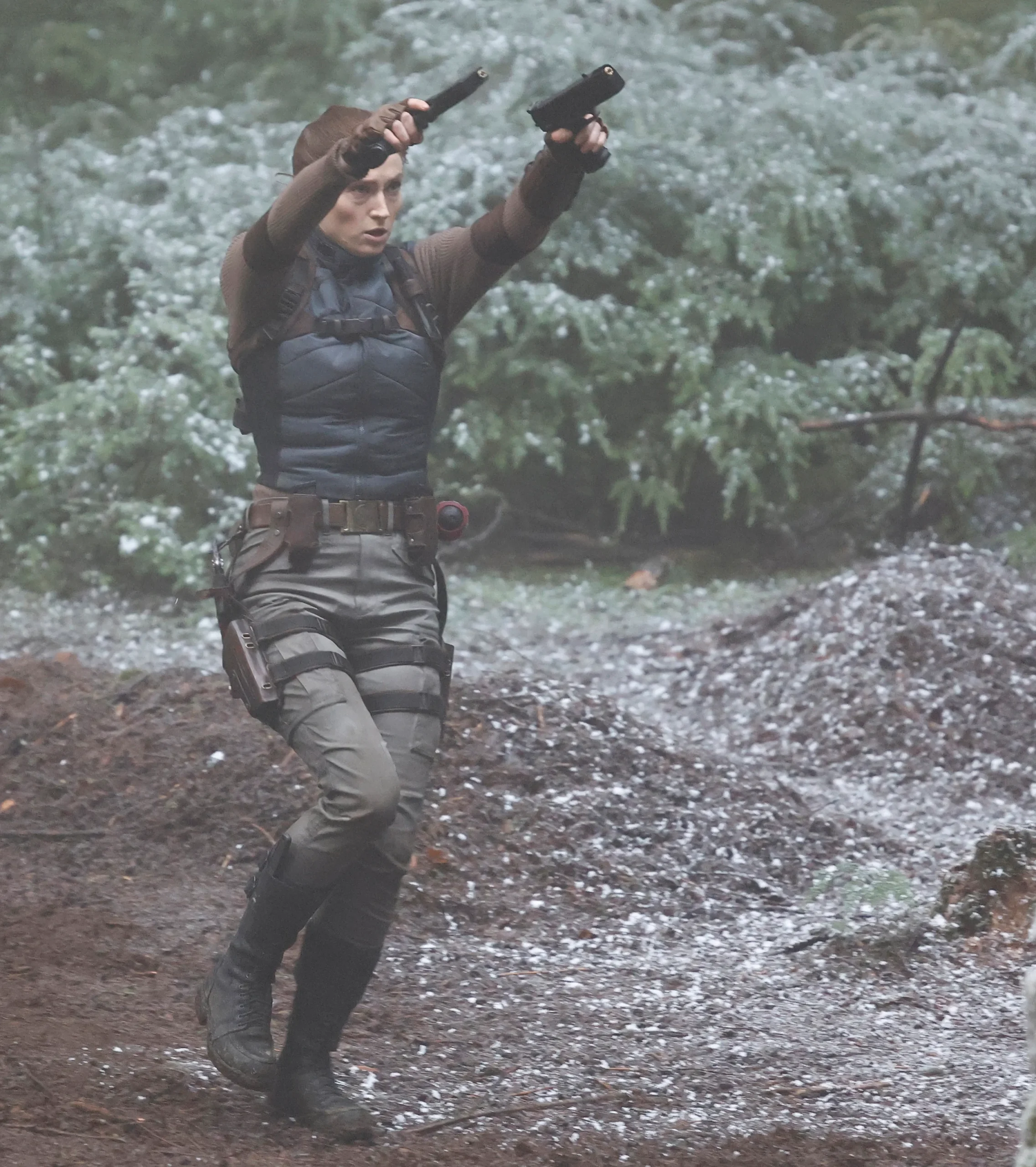 Turner as Lara Croft aiming dual pistols during an on-set action sequence.
