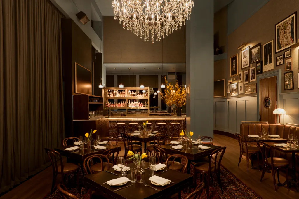 Interior of Estelle's restaurant in the Meatpacking District, with bar, chandelier and dining tables.