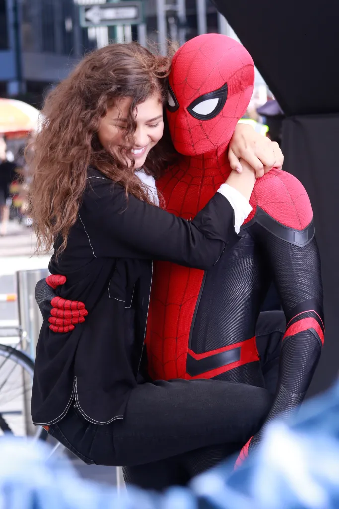 Tom Holland, in a Spider-Man suit, holding Zendaya who is smiling.