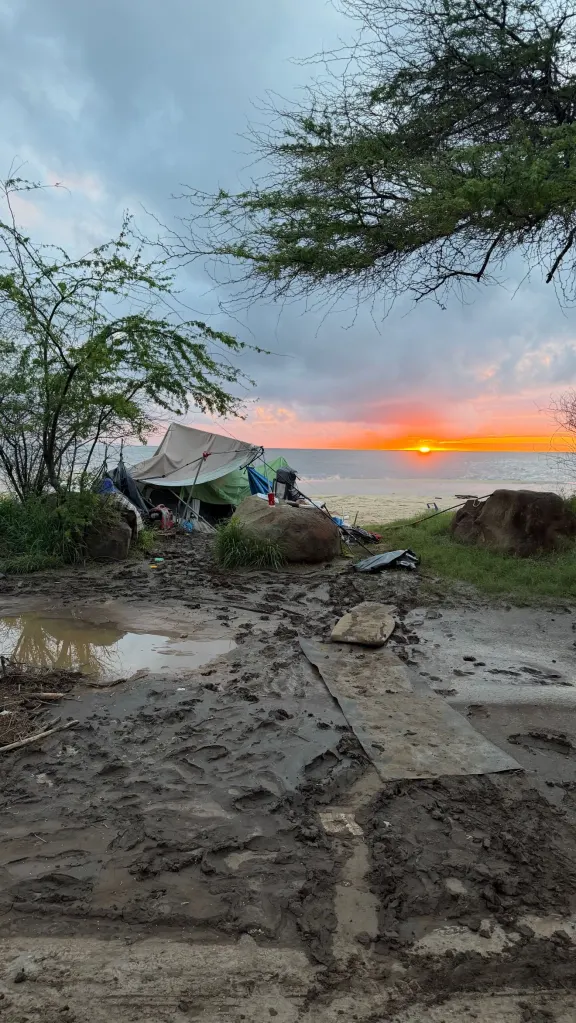 Muddy beach campsite with tents after flooding on Oahu's North Shore.