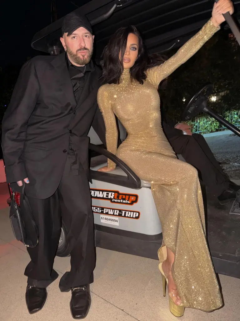 Kim Kardashian in a gold gown posing with Demna Gvasalia outside the Vanity Fair Oscars Party.
