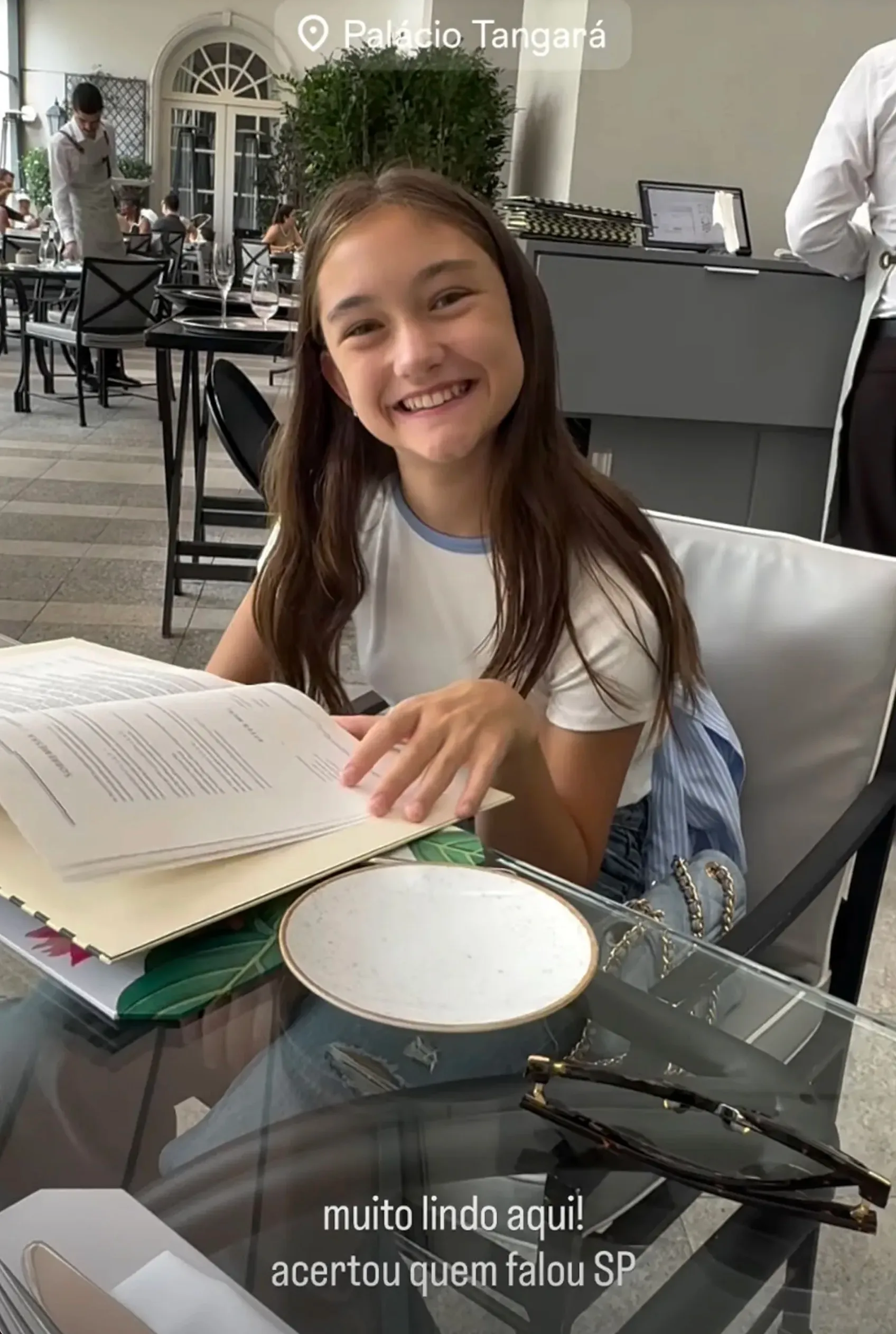 An 11-year-old girl smiling while looking at a menu in a restaurant.