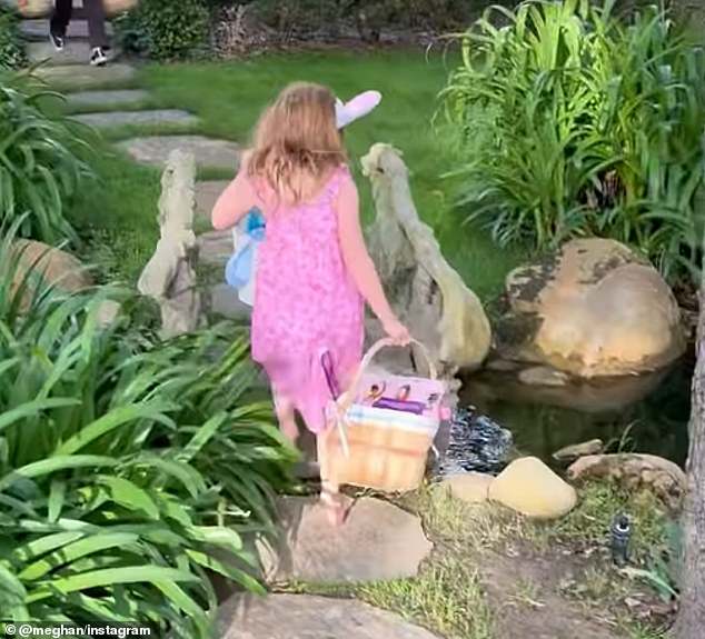Lilibet wearing bunny ears carries a basket during an Easter egg hunt in the Sussexes' Montecito garden