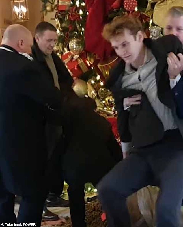 Security staff remove a Take Back Power protester after manure was dumped beneath the Ritz lobby Christmas tree