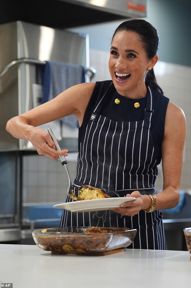 Meghan Markle serving food at a Melbourne homeless shelter, wearing gold jewelry