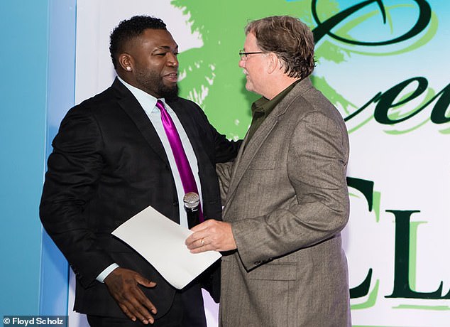 Floyd Scholz presents his custom wood carving to baseball legend David Ortiz, known as 'Big Papi,' during the slugger's Celebrity Golf Classic after creating a piece honoring his life and legacy