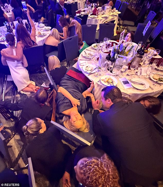 Panicked attendees take cover under tables after gunshots rang out in the ballroom