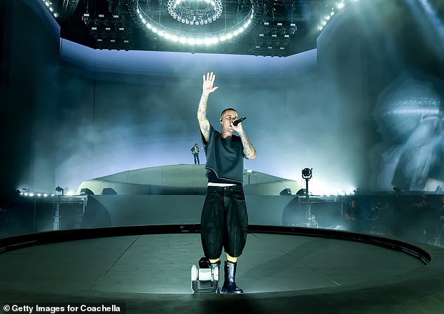 Justin Bieber with his hood off raises his arm during the Coachella set