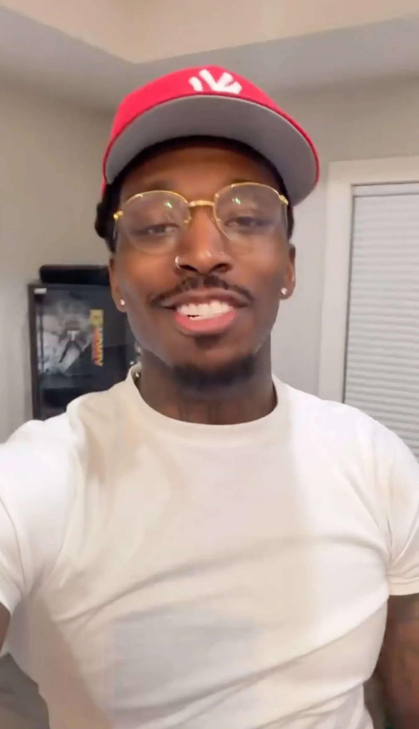 Pardison Fontaine smiling in a red baseball cap and glasses.