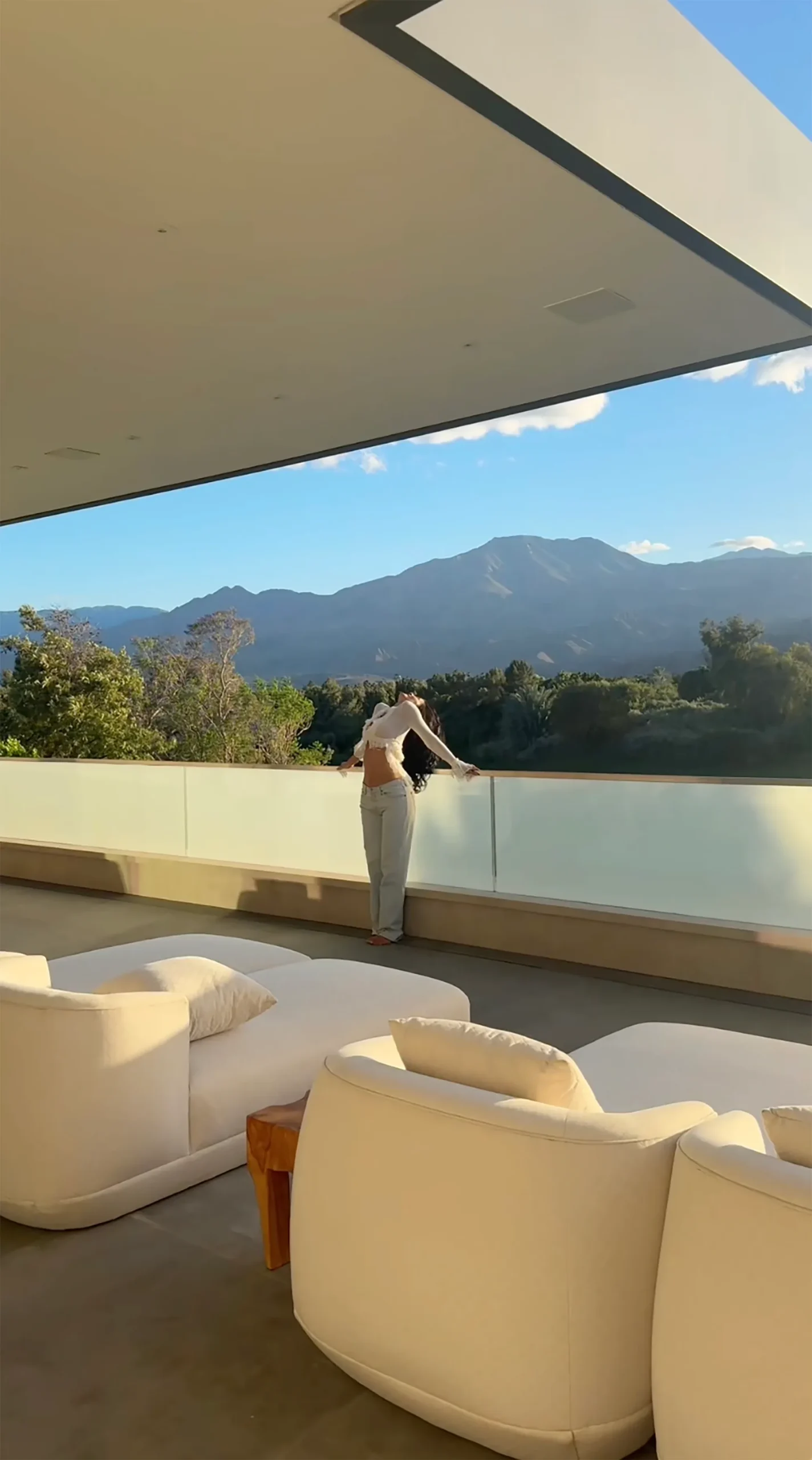 Kylie Jenner standing on a balcony with a mountain view.