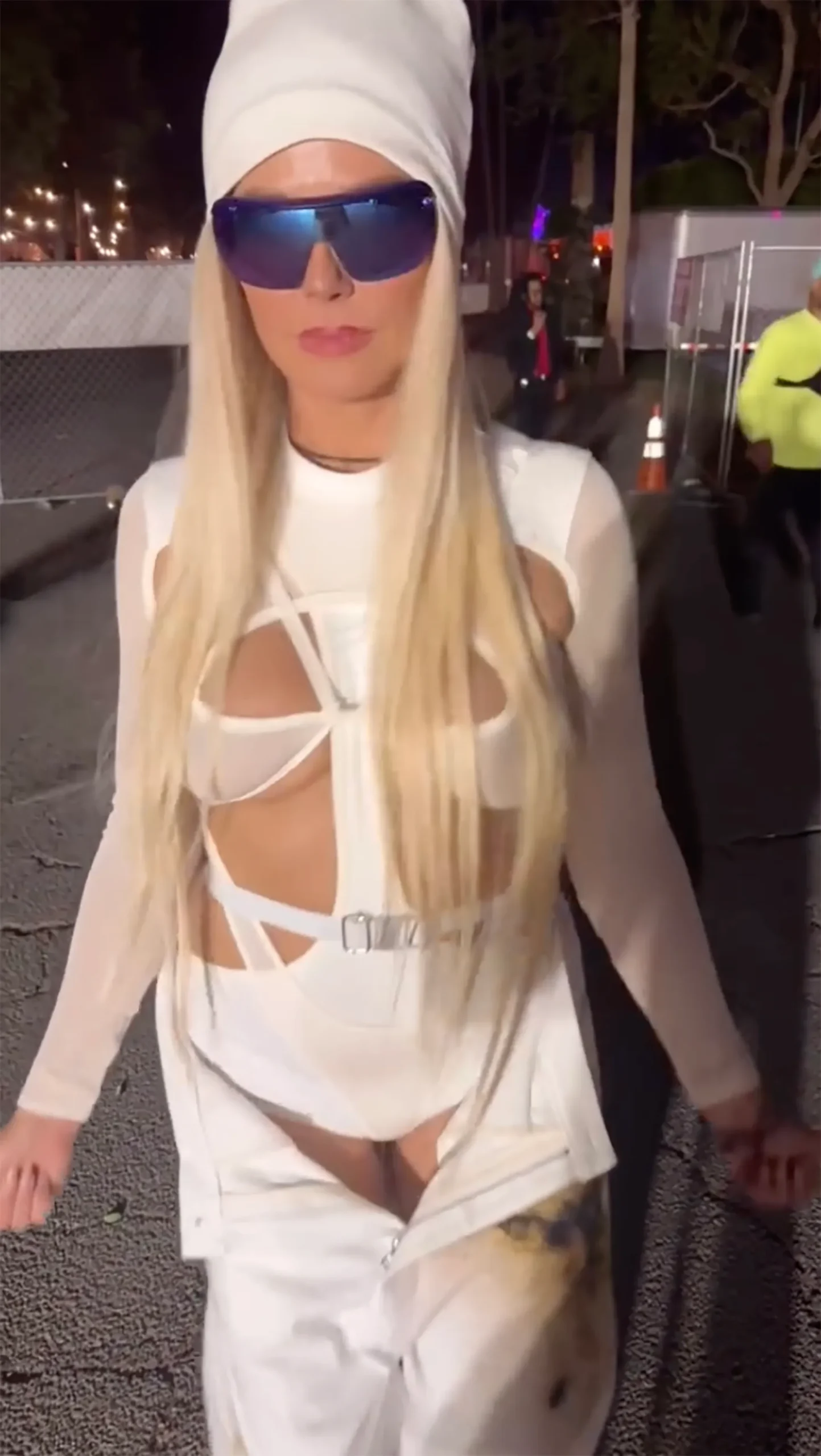 Heidi Klum in an all-white cutout bodysuit with blue sunglasses and a white beanie at Coachella.