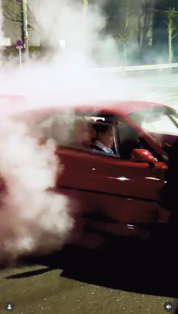 A red Ferrari drifts, emitting large clouds of smoke, with Lewis Hamilton and Kim Kardashian inside.