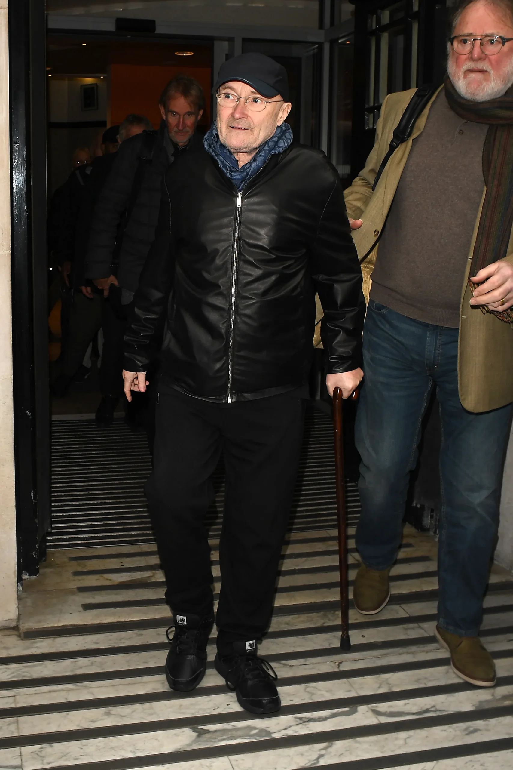 Phil Collins leaving BBC Radio 2, using a walking stick.