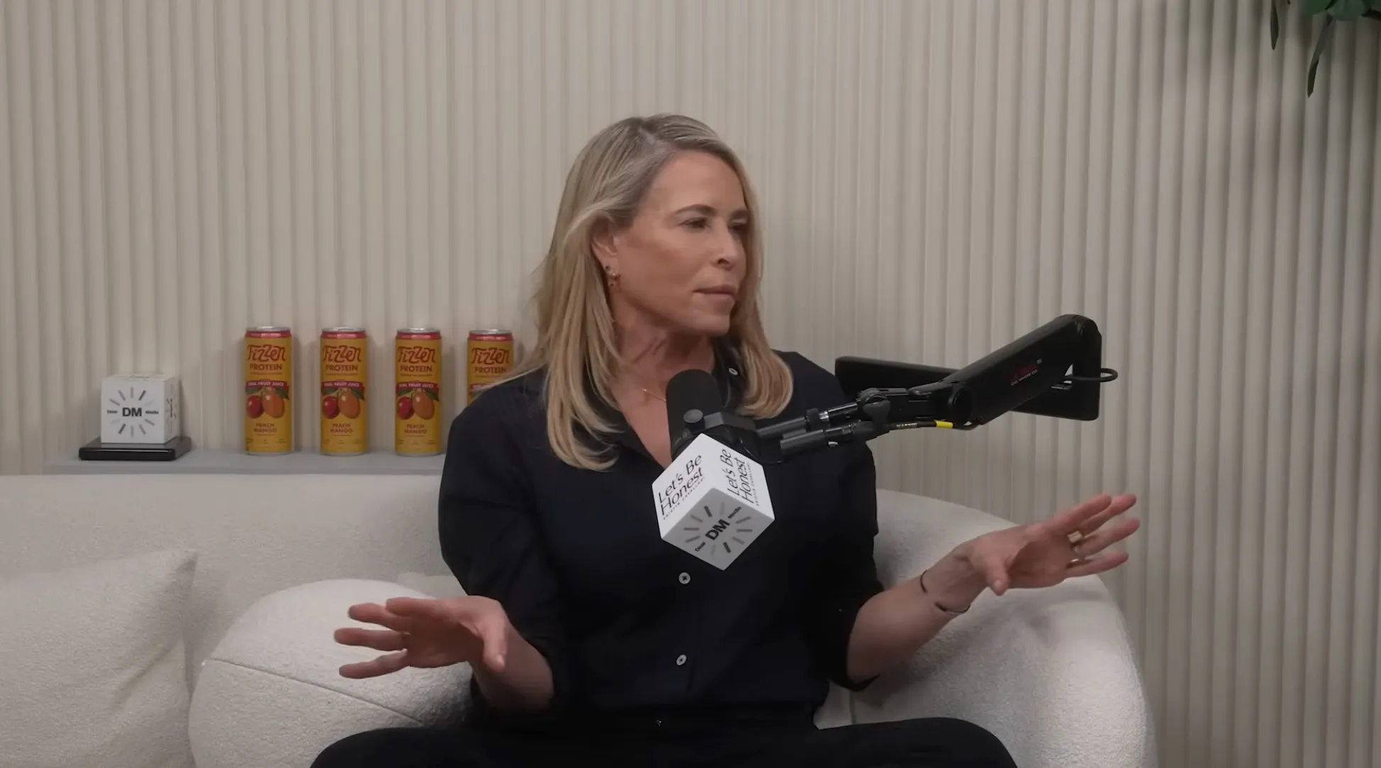 Chelsea Handler speaking into a microphone during the Let's Be Honest podcast.