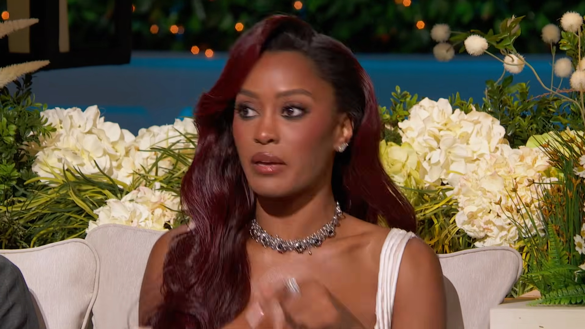 Ciara Miller with long red hair and a white top reacting during the reunion.
