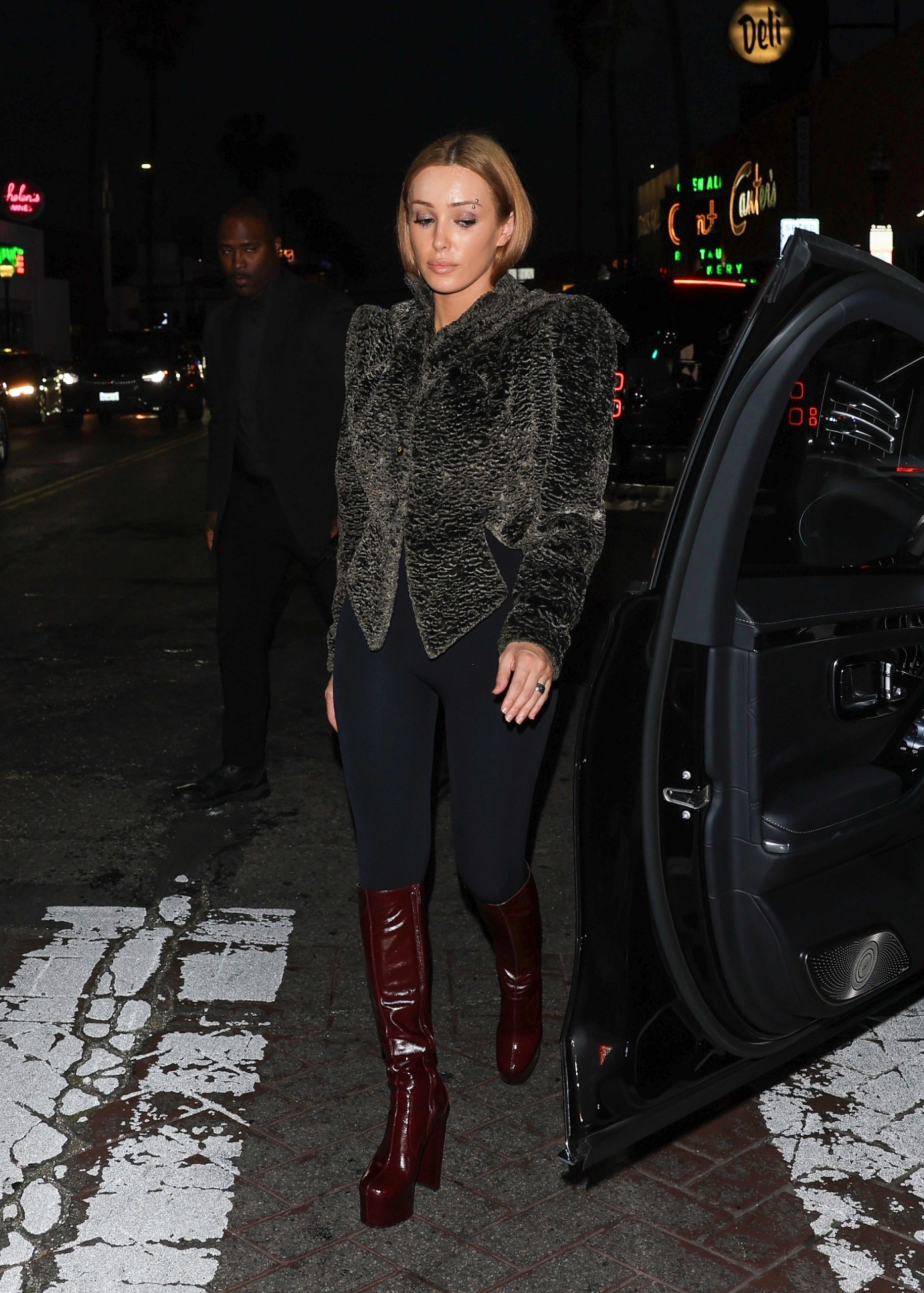 Bianca Censori in a more covered-up look with jacket, leggings, and platform boots during a Los Angeles night outing.