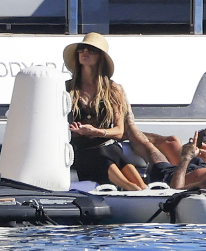 Victoria Beckham in a straw hat and black coverup on a yacht in Ibiza.
