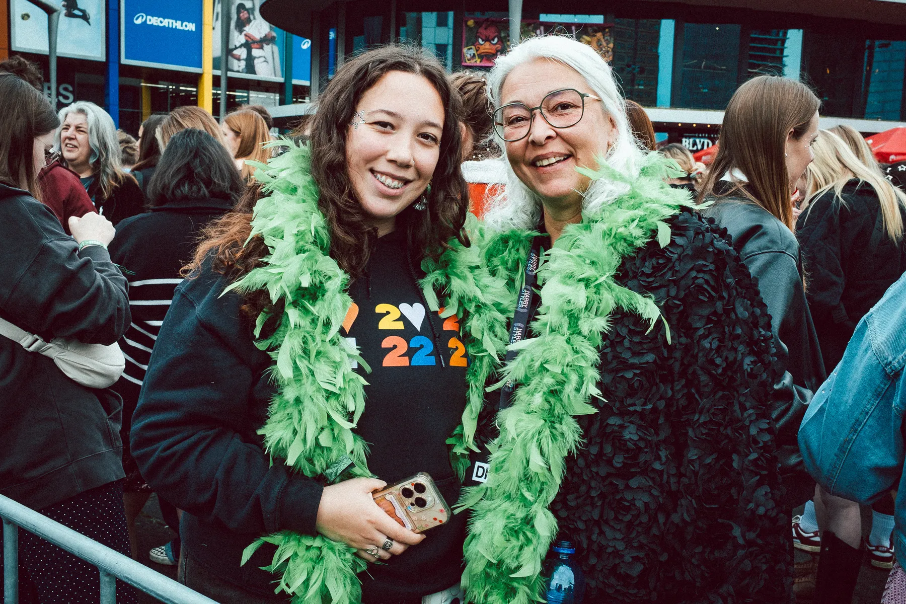 Two fans in vibrant outfits celebrate together in the crowd before the show.