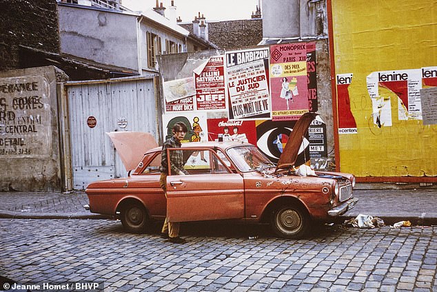 Vintage car halted on a cobbled street lined with political posters