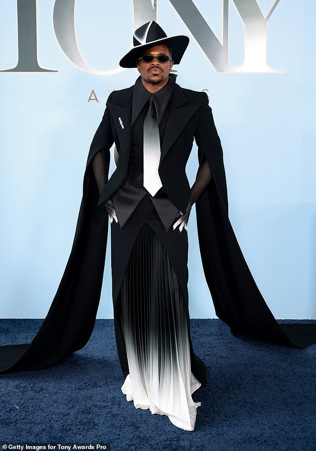 Jeremy Pope at the 2026 Tony Awards wearing a black button-down top, black-and-white skirt, fedora, and sunglasses.