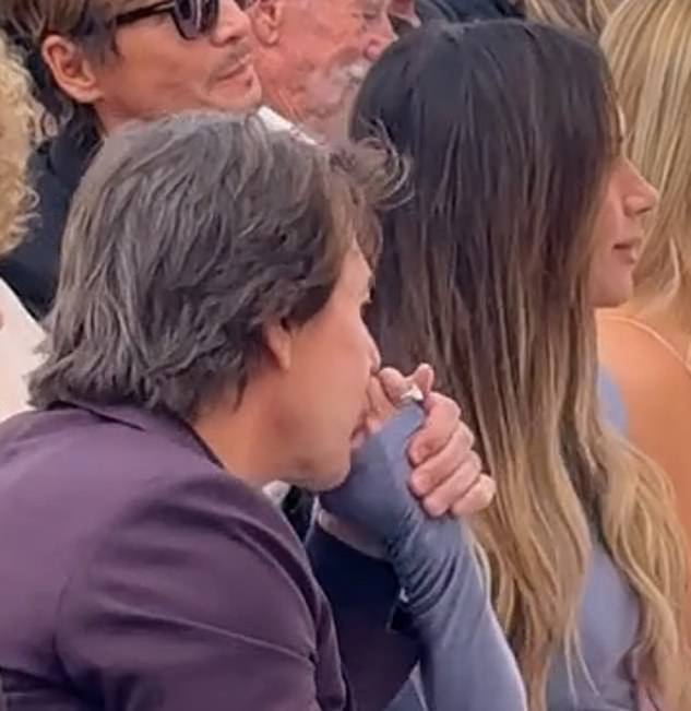 Tom Cruise kisses Victoria Beckham's hand as they sit with the Beckham family during David's Walk of Fame ceremony