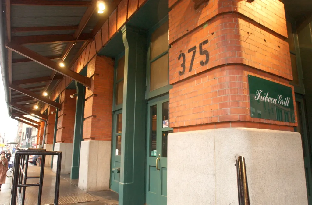 Exterior of the Tribeca Grill restaurant with brick walls, green trim, and an awning over the sidewalk.