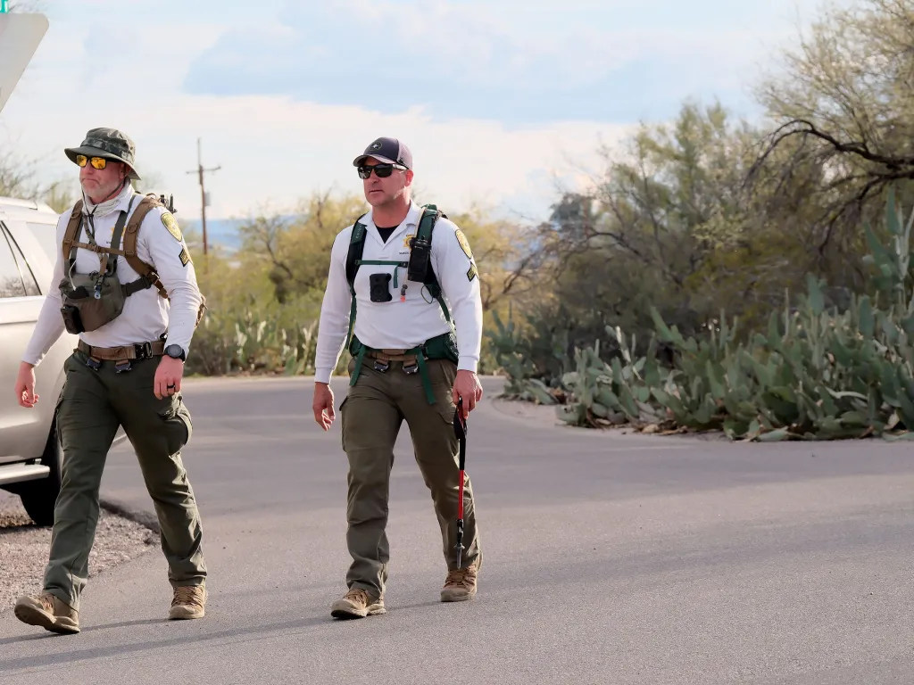 Two FBI agents walk down a road during the search for Nancy Guthrie.