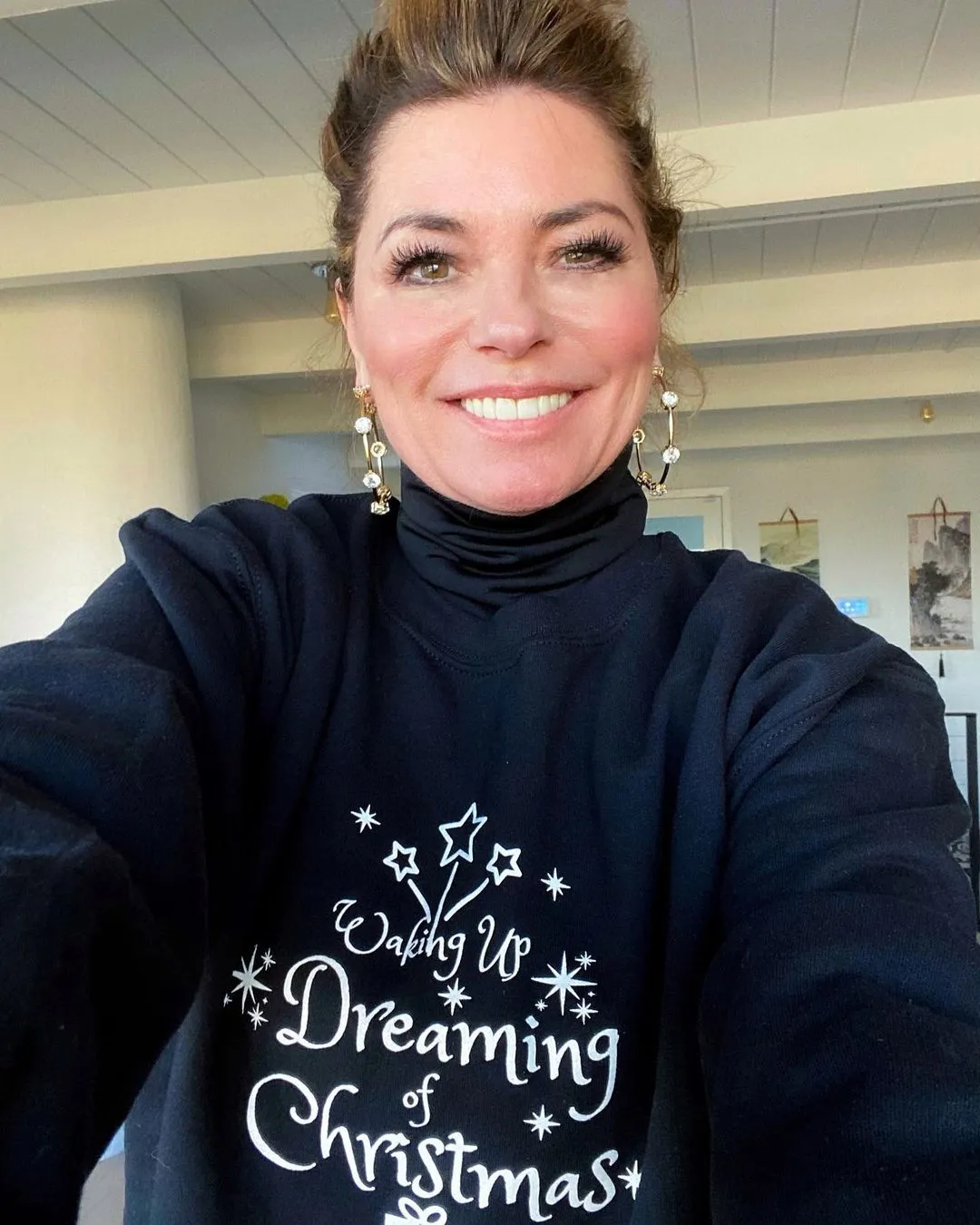 Shania Twain wearing a black "Waking Up Dreaming of Christmas" sweater.