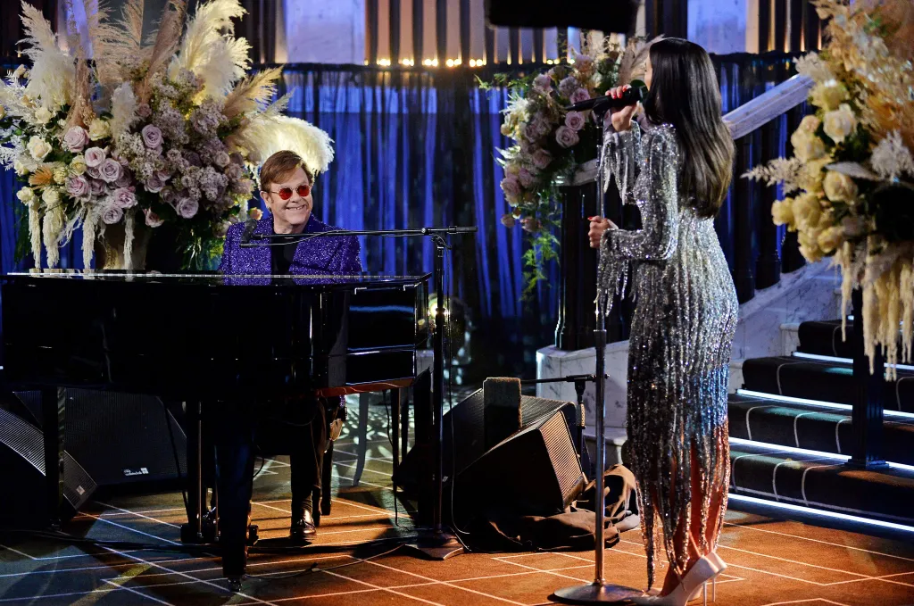 Elton John at the piano with Dua Lipa singing during a past performance.
