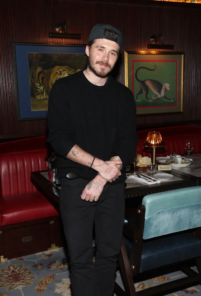 Brooklyn Beckham in a dark restaurant with a reserved table in front of him.
