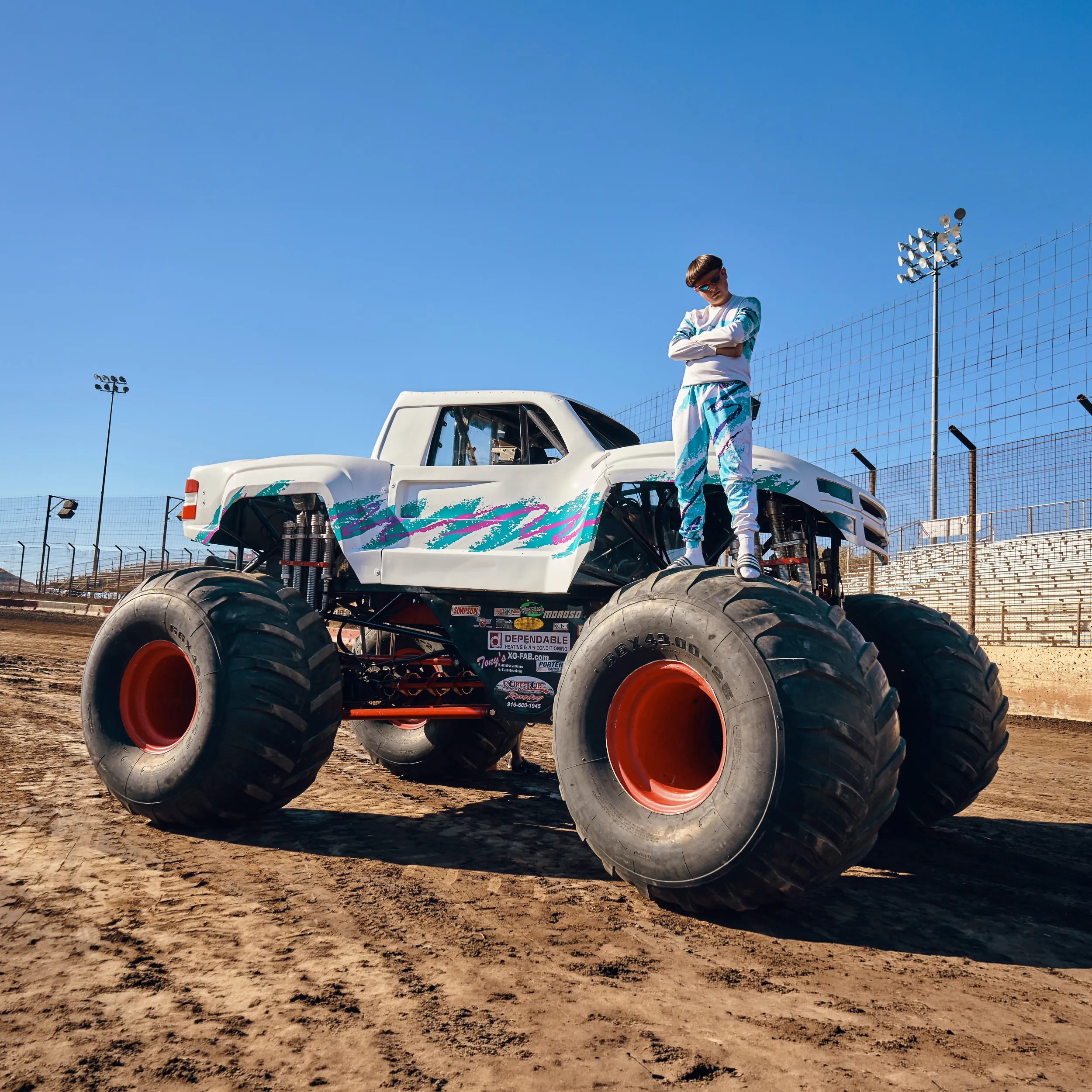 Oliver Tree standing atop a monster truck in a dramatic pose