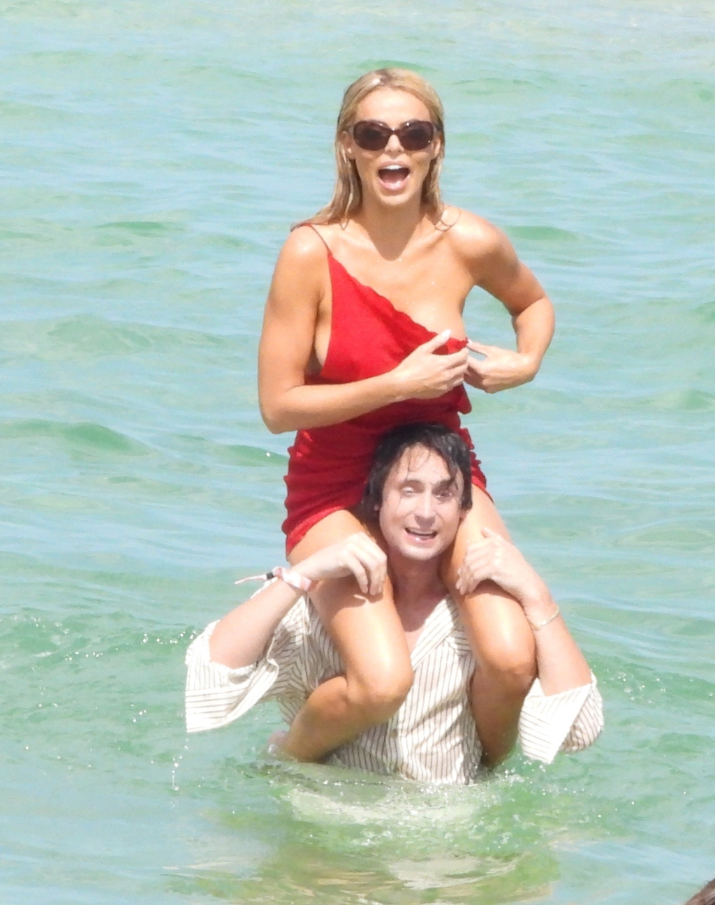 In Miami during Swim Week, Brooks Nader is carried on a friend's shoulders in the ocean after a wardrobe malfunction.